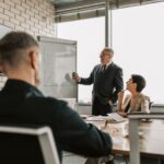A senior leader presents growth charts to colleagues in a boardroom meeting