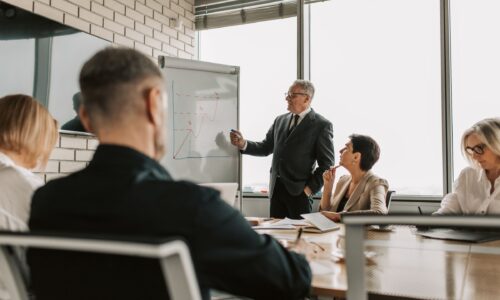 A senior leader presents growth charts to colleagues in a boardroom meeting