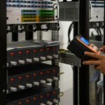 Technician inspecting a server rack with a handheld diagnostic tool
