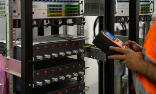 Technician inspecting a server rack with a handheld diagnostic tool